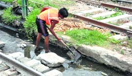 A boy cleans a drain along the track at the railway station in Jammu.