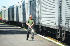 A pro-Russian separatist walks near a carriage as monitors from the Organisation for Security and Cooperation in Europe and members of a forensic team arrive to inspect the train, containing the remains of victims from the downed Malaysia Airlines Flight MH17, in Torez on Monday