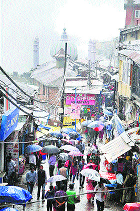 Pedestrians walk with umbrellas in the Lower Bazar in Shimla on Tuesday.