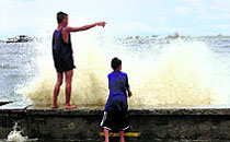 Boys watch waves slamming along a bay brought by Typhoon near Manila on Tuesday