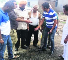 Shopkeepers and residents of the railway road area show the deplorable condition of the road to the Vigilance officials in Jalandhar on Wednesday