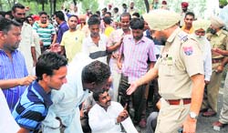 A police official tries to remove protesters from near Ladhowal Toll Plaza on the National Highway-1 in Ludhiana on Wednesday. Tribune Photo: Himanshu Mahajan