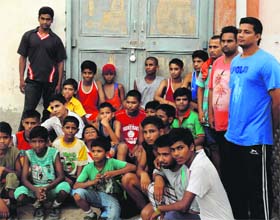 Budding boxers sit outside the locked boxing hall at the Multipurpose Sports Stadium in Bathinda on Thursday.