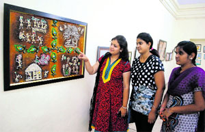 Girls have a look at a painting at an exhibition held at the art gallery in Amritsar on Sunday.