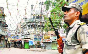A security man guards a street during curfew in Saharanpur on Sunday