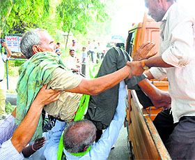 A beggar being picked up by officials while others await alms outside Shri Durga Mata Mandir