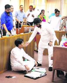 BJP councillor Saurabh Joshi sits on the floor in protest while Congress councillor Pradeep Chhabra requests him to get up during the MC General House meeting at the MC office in Sector 17, Chandigarh, on Monday.