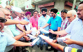 Members of Industrial and Traders Joint Action Committee and Punjab Motorparts Association burn copies VAT Act, Section 13(1), in Jalandhar on Monday.