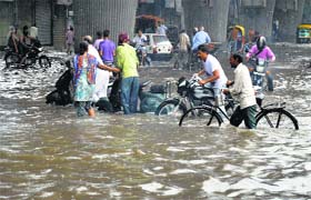 Commuters make way through a waterlogged road near Clock Tower in Ludhiana