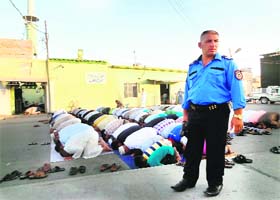 An Iraqi policeman stands guard as Muslim worshippers perform the morning prayer at a mosque in Kirkuk on Monday