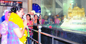 Navjeet Kaur Dhillon, who returned home after winning a bronze medal in the World Junior Championship held in the US, pays obeisance at a model of the Golden Temple at the railway station in Amritsar on Wednesday.