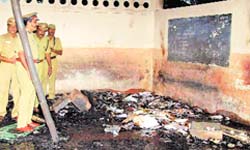 Police officers inspect the burnt remains of a school building in Kumbakonam. file photo