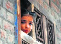 A girl looks outside from a window during curfew at Saharanpur on Tuesday. Tribune Photo: Nitin Mittal