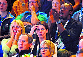 Usain Bolt (R) of Jamaica applauds as he sits in the crowd and watches the netball match between Jamaica and New Zealand in Glasgow. 