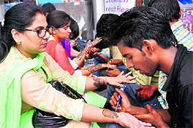Women get henna designs made on their palms at Paltan Bazaar on the occasion of Teej festival in Dehradun on Wednesday. 