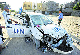 Palestinians gather around a United Nations aid agency car that was damaged by shrapnel from an Israeli strike, in the Jebaliya refugee camp, northern Gaza Strip, on Tuesday.