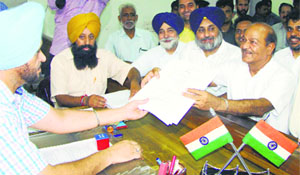 Bhagwan Dass Juneja , SAD-BJP candidate, files his nomination papers in Patiala on Thursday as Deputy CM Sukhbir Badal and minister Sikander Maluka look on .