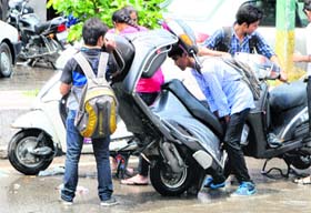 Students try to drain out water from the exhaust pipe of their scooters after showers in Amritsar on Friday.