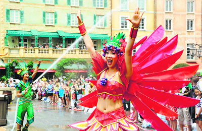 A Tokyo Disney Sea cast member (L) uses a hose to spray water towards guests while a dancer performs during a special summer attraction called “Minnie’s Tropical Splash” at Tokyo Disney Sea in Urayasu, suburban Tokyo. Tokyo’s temperatures climbed 33 degrees Celsius as the rainy season in Tokyo metropolitan area ended. More than 3,000 persons had to be taken to hospitals due to heat stroke or heat exhaustion recently.