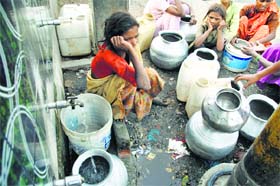 People wait their turn to fill their containers with water from a community tap at Narwal in Jammu