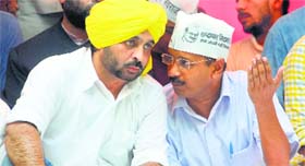 AAP chief Arvind Kejriwal speaks to MP Bhagwant Maan at a rally in New Delhi on Sunday.