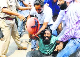 The turban of a protester flies off in the melee.