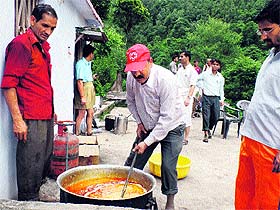 Shantikunj volunteers prepare food for people affected by flash floods near Ghansali in Tehri district on Sunday.