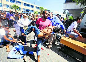 A Palestinian carries a wounded boy following an Israeli air strike on a UN-run school, where displaced Palestinians are taking refuge, in Rafah in the southern Gaza Strip on Sunday.
