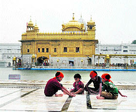 Children enjoy themselves in the rain at the Golden Temple parikarma in Amritsar on Monday.
