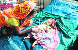 A three-month-old infant, suffering from Japanese Encephalitis, being comforted by her mother at a hospital in Siliguri, West Bengal. photo: AFP