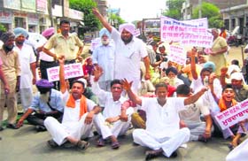 Activists and office-bearers of the Ahmedgarh Bachao Morcha stage a dharna on Pohir Road in Mandi Ahmedgarh on Monday