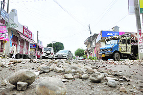 A road strewn with stones due to flooding after rain in Jammu.