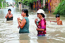 Residents carry packets of food as they wade through flood waters in a village northwest of Manila on Tuesday. Typhoon Halong has intensified monsoon rains resulting in flooding in several parts of northern Philippines