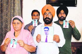 Family members of Harmanpreet Singh show his photographs to the media  in Amritsar on Wednesday