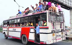 Passengers travel atop a private bus on the Bathinda-Barnala road on Wednesday. 