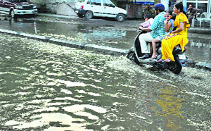 A scooterist wades through a waterlogged road in Patiala on Wednesday. 