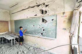 Picking up the pieces: A Palestinian boy writes on a shrapnel-riddled blackboard at a heavily damaged Sobhi Abu Karsh school in Gaza Citys al-Shejaea neighborhood on Wednesday