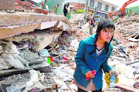 An earthquake survivor walks through the rubble of collapsed houses at Longtoushan, Yunnan province, on Wednesday