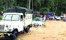 Vehicles cross the flooded Dhaliara Khud on Friday