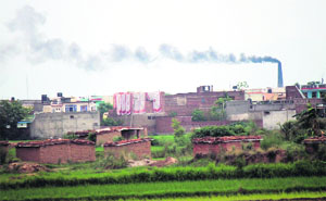 Smoke billows out of the chimney of a brick kiln near a residential area at RS Pura village in Jammu.