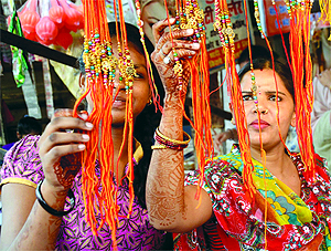Women buy 'rakhis' from a roadside shop on the eve of Raksha Bandhan in New Delhi on Saturday