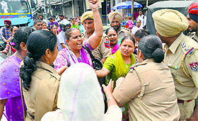 Police personnel pacify protesting anganwadi workers near the ISBT in Ludhiana.
