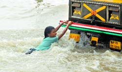 Monsoon Mania: A girl plays as she holds onto an auto on the flooded banks of the Ganga after heavy rains in Allahabad on Saturday. Monsoon rainfall was 18% above average in the past week after rainfall of 9% below average in the previous week. Reuters