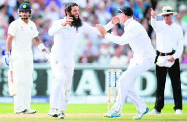 Moeen Ali celebrates with teammate Joe Root after dismissing Cheteshwar Pujara during the fourth Test match at Old Trafford on Saturday.