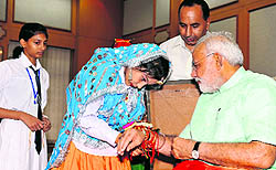 Sahiba Sethi, a student of DAV Public School, Ratia, ties a rakhi to Prime Minister Narendra Modi at his official residence in Delhi on Sunday