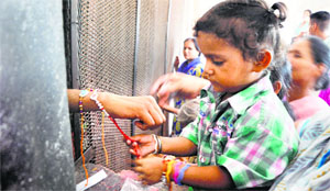 A child ties Rakhi around the wrist of jail inmate at the Ludhiana Central Jail on Sunday.