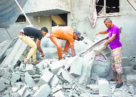 Palestinians remove debris from the wreckage of a car after a house was hit by an Israeli military strike in Rafah on Sunday
