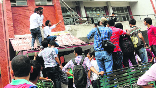 (Clockwise from top) Workers of a party climb atop a roof to address the gathering at the UIET canteen