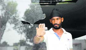 A man looks at a windowpane damaged by a mortar shell fired by the Pakistan Rangers at Pindi village of Arnia sub-sector, RS Pura, in Jammu on Monday.