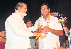 Chief Minister Harish Rawat congratulates Chaman Singh during the oath-taking ceremony in Dehradun on Monday.